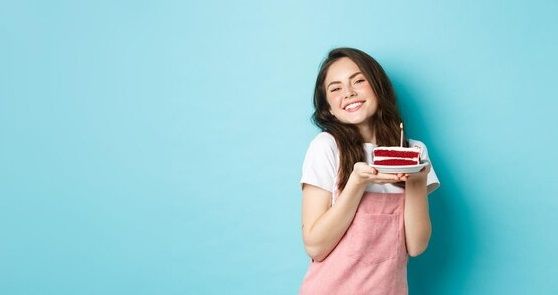 holidays-and-celebration-cute-glamour-girl-celebrating-her-birthday-holding-plate-with-cake-and-smiling-cheerful-celebrating-standing-over-blue-background_1258-123601.jpg