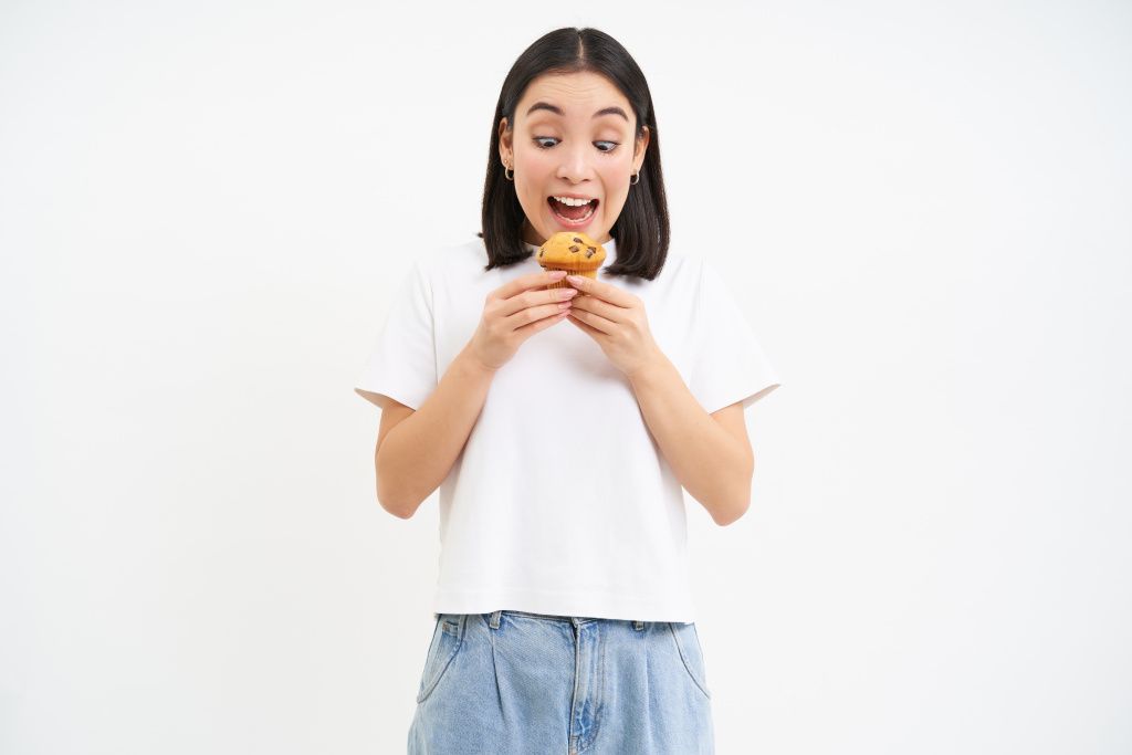 image-of-funny-asian-woman-eating-delicious-cupcake-likes-pastry-munching-dessert-with-delight-white.jpg