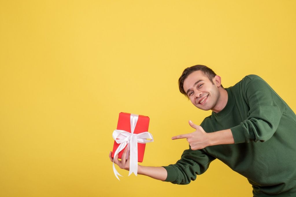 front-view-happy-young-man-pointing-gift-yellow_179666-10367.jpg