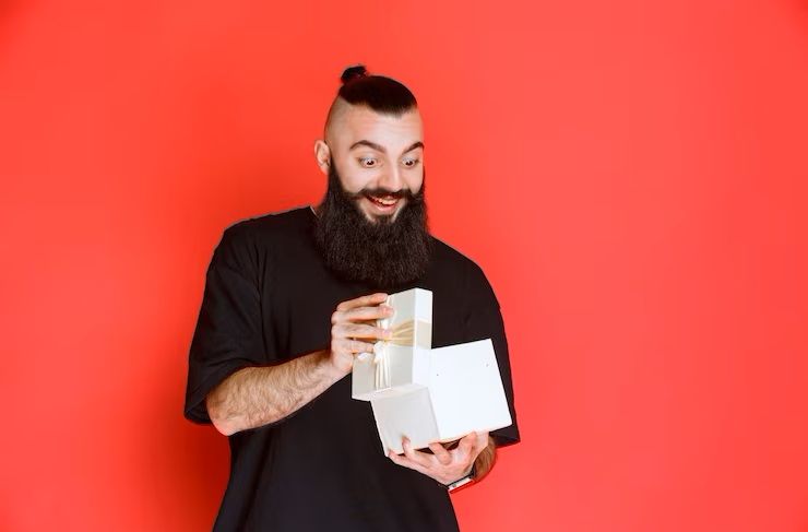 man-with-beard-holding-a-white-gift-box-and-opening-it-with-excitement_144627-57350.jpg