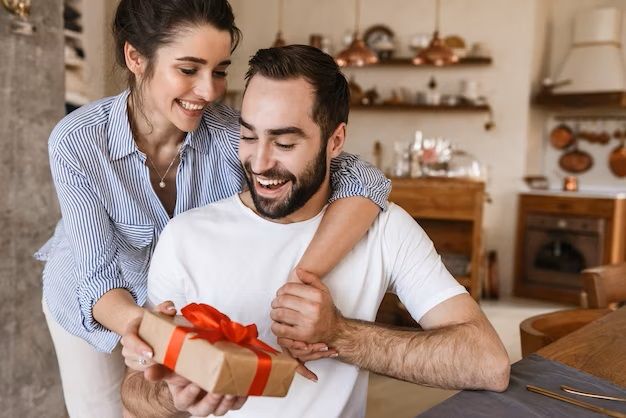 attractive-brunette-couple-man-and-woman-having-breakfast-in-apartment-while-sitting-at-table-with-present-box_171337-60194.jpg