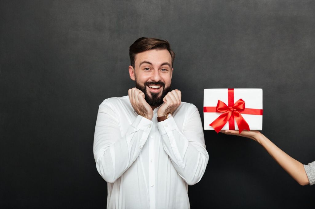 portrait-excited-brunette-man-rejoicing-get-white-gift-box-with-red-bow-from-female-hand-dark-gray-wall_171337-607.jpg